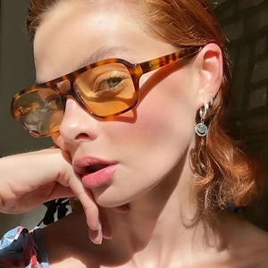 Retro tortoiseshell sunglasses with orange lenses and a smiling face pendant earring