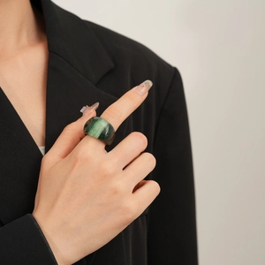 Macro detail of a wide marble-textured dark green resin ring worn on a finger
