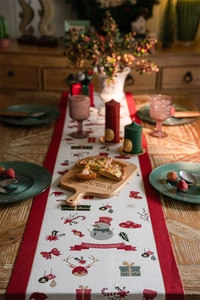 Close-up of festive Christmas table runner with snowman patterns on a wooden dining table