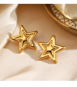 Close-up of golden star-shaped stud earrings on elegant silk background fabric
