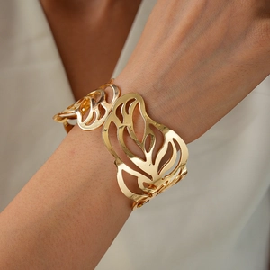 Macro shot of a gold hollow-out leaf pattern bangle on a female wrist for a chic look