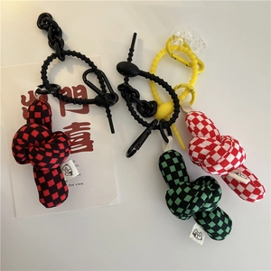 Detailed view of colorful checkered knot bag charms with plastic chains and cat labels