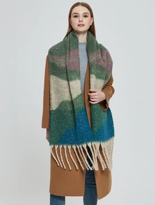 Detail of chunky knit scarf showing multi-colored stripes and thick beige fringe texture