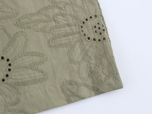 Macro detail of olive green floral embroidery and eyelet hollow design on fabric