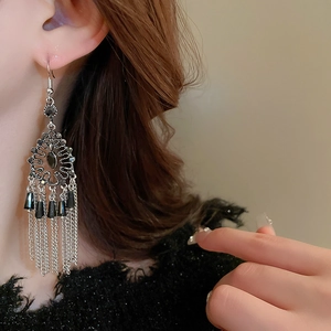 Vintage bohemian silver tassel earrings with black gemstones worn by a model