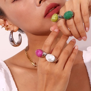 Close-up of model wearing various colorful acrylic stone rings and gold jewelry accessories