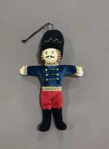 Detail of plush nutcracker ornament with velvet uniform and gold braided trim decoration