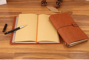 Retro brown leather traveler notebook with gold pen and blank kraft paper inserts