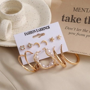 Detail of 6-piece earring set featuring gold hoops, stars, moon, and pearls on paper