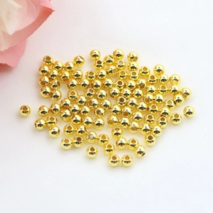 Polished 18k gold-plated round metal beads for DIY jewelry making on white fabric