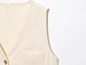 Détail du haut de blazer sans manches abricot avec bouton doré et étiquette de taille S