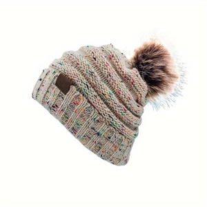 Détail du bonnet en tricot avec motif confettis colorés et pompon en fausse fourrure