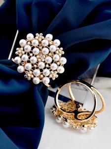 Detailed macro of a golden flower scarf clip with cream pearls and sparkling rhinestones