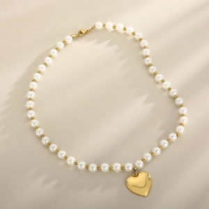 Détail d'un collier de perles avec un pendentif cœur doré sur fond neutre