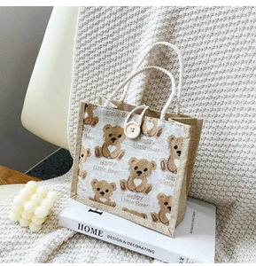 Detail of linen tote bag featuring a cute brown bear print and white rope handle
