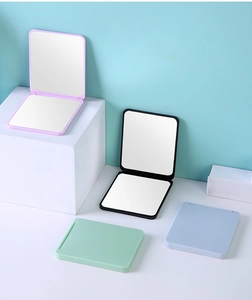 Close-up of portable square folding makeup mirrors in four pastel colors on geometric stands