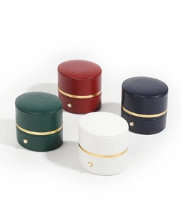 Cylindrical jewelry box detail showing dark green, red, navy, and white options