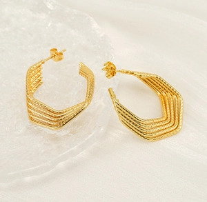 Detail of 18k gold plated multi-layer textured earrings on a premium silk background