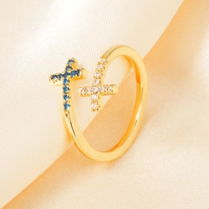 Elegant gold adjustable ring with blue and white zircon cross charms on silk background