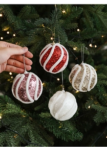 Detail von glitzernden Weihnachtskugeln mit Plüschstreifen an einem leuchtenden Baum