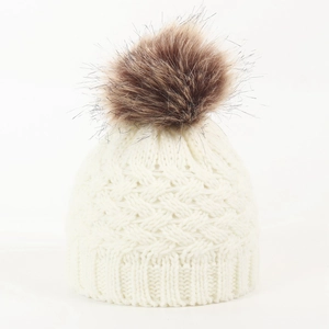 Detail of off-white knit texture and fluffy brown faux fur pompom on infant winter hat