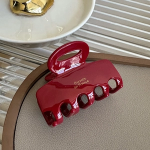 Detail of dark red acetate shark hair claw clip with golden Barrette La France text
