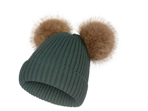 Détail d'un bonnet en maille vert foncé avec deux pompons en fausse fourrure marron