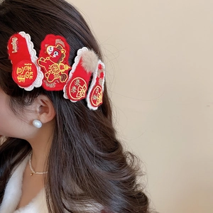 Close-up of red festive embroidery hair clip with white lace and brown plush pompom detail