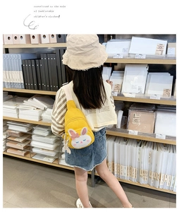 Detailed view of yellow canvas kids chest bag with rabbit pattern and white tassel