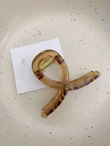 Vue détaillée d'une pince à cheveux motif écaille avec ressort doré sur plateau céramique