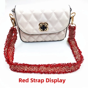 Detail of adjustable red and gold woven strap with gold buckle on a white quilted bag