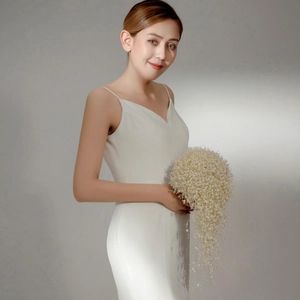 Elegant bridal cascade bouquet featuring white pearls held by a model in a slim wedding dress