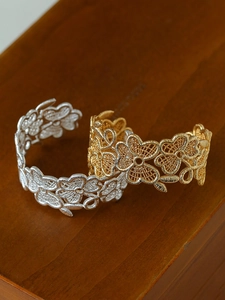 Close-up of 18k gold and silver plated open bangles with vintage clover floral patterns
