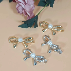 Close-up of four metal bow hair clips in gold and silver with pearl accents