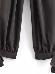 Detailed close-up of the black bow-tie cuffed hem on casual high-waist lantern pants