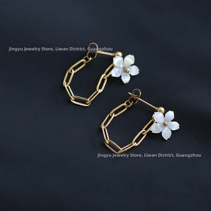 Detail of 18K gold-plated titanium earrings with white shell flower and dangling chain
