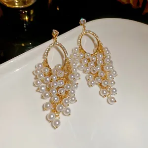 French vintage grape cluster earrings with pearls and crystals on a white ceramic surface