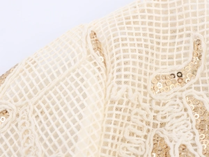 Detailed view of champagne mesh fabric with gold sequins and elegant embroidery