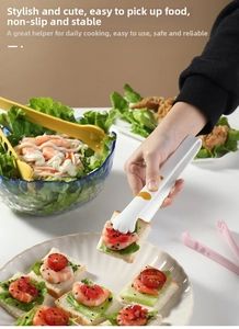 Close-up of cute cat paw silicone food tongs picking up a fresh sandwich on a plate
