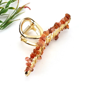 Macro shot of gold alloy hair claw clip featuring natural red crystal stone fragments