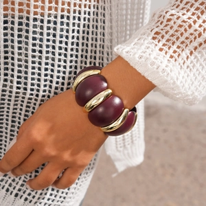 Detail view of chunky geometric acrylic bracelet in dark purple and gold on female wrist