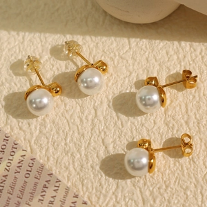 Elegant 2024 French style white pearl stud earrings with gold metal base on beige surface