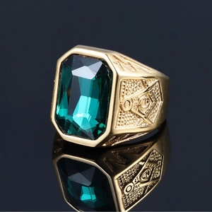 Macro shot of gold Masonic ring with large emerald stone and detailed side engravings