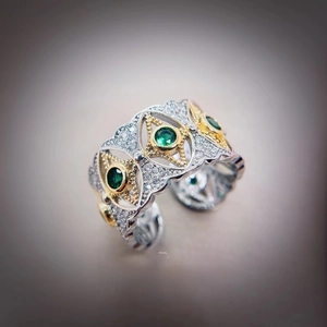 Macro view of vintage two-tone wide band ring with green emeralds and pavé crystals