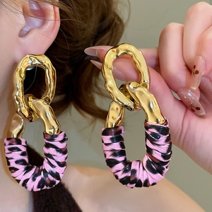 Detail view of interlocking geometric oval earrings with hammered gold metal and leopard print