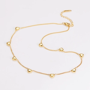 Detailed view of a gold heart charm necklace with lobster clasp on white background