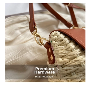 Close-up of woven straw texture with brown leather strap and gold metal hardware