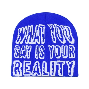 Detail of royal blue beanie with WHAT YOU SAY IS YOUR REALITY text in white jacquard
