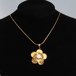 Detail of 18K gold flower pendant with white pearl on a black velvet display stand