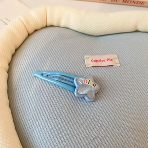 Détail d'une pince à cheveux étoile bleu clair avec lettrage nice sur fond de tissu doux